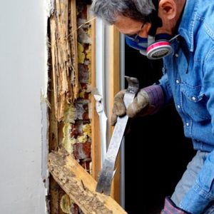 Man inspecting the damage caused by termites around a door opening